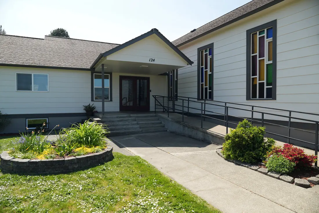 The front entrance of Redeemer Covenant Church with steps and an accessible ramp
