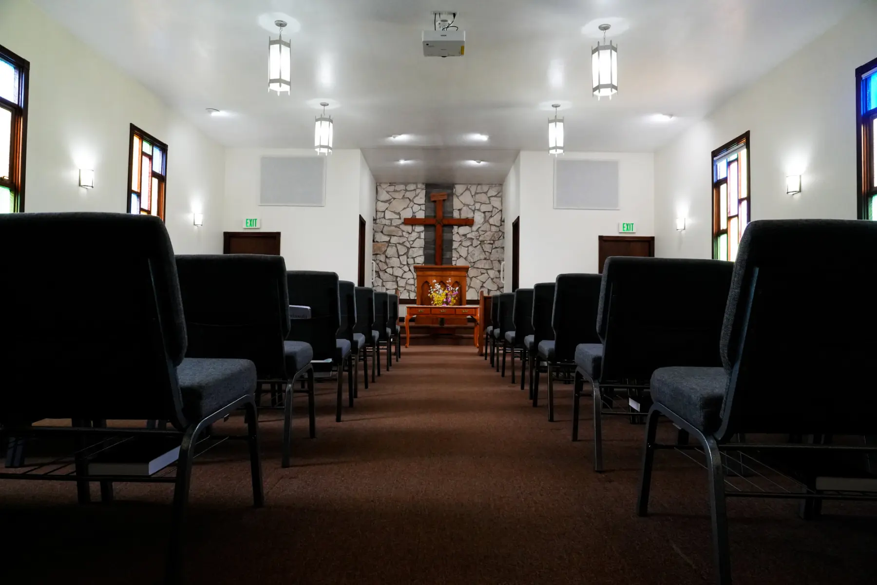 The sanctuary at Redeemer Covenant Church, with rows of chairs facing a wooden cross on a stone wall